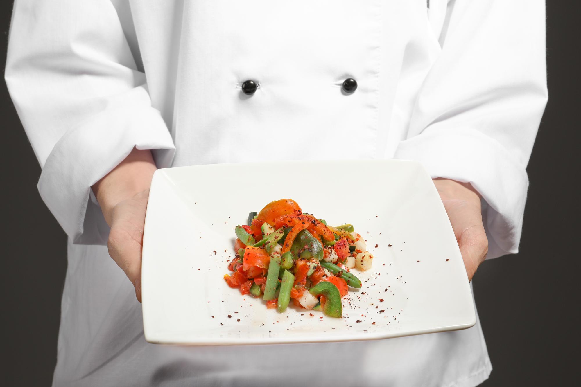 Chef demonstrating plating on a warm kitchen counter